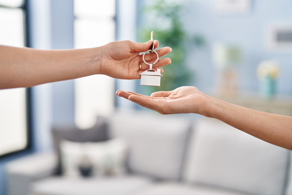 Young,Woman,Holding,Key,Of,New,House,At,Home